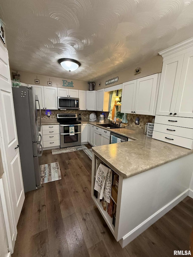 501 N Cambridge Dr, Desoto, IL 62924 - kitchen with appliances with stainless steel finishes, a peninsula, white cabinetry, tasteful backsplash, and dark wood-style floors