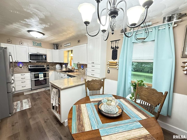 501 N Cambridge Dr, Desoto, IL 62924 - kitchen with stainless steel appliances, white cabinets, a peninsula, a chandelier, and dark wood-type flooring
