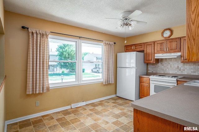4718 19th Ave, Moline, IL 61265 - kitchen with white appliances, under cabinet range hood, ceiling fan, tasteful backsplash, and brown cabinets
