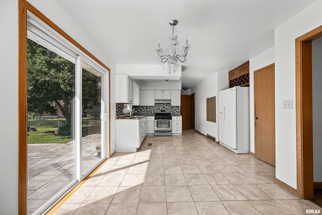 2525 4th St Unit A, East Moline, IL 61244 - kitchen with white refrigerator with ice dispenser, stainless steel range oven, under cabinet range hood, tasteful backsplash, and a chandelier