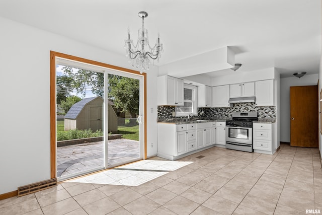 2525 4th St Unit A, East Moline, IL 61244 - kitchen with stainless steel gas range oven, under cabinet range hood, a chandelier, tasteful backsplash, and white cabinets