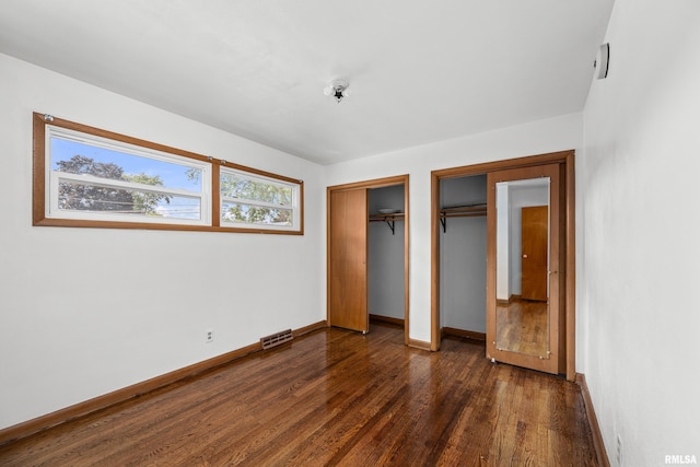 2525 4th St Unit A, East Moline, IL 61244 - unfurnished bedroom featuring dark wood-type flooring and two closets