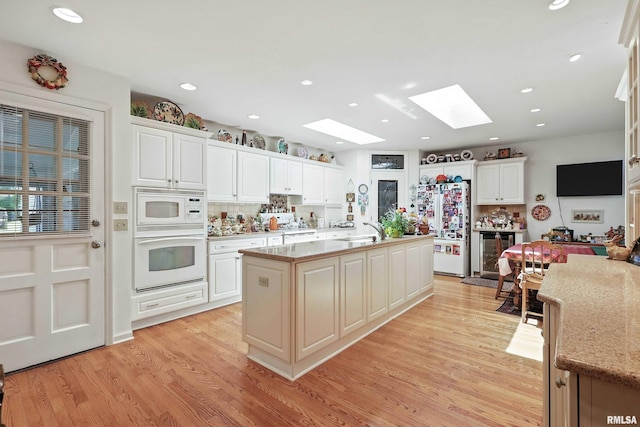 1928 Fernwood Ave, Davenport, IA 52803 - kitchen with white appliances, a skylight, wine cooler, light wood-style floors, and a center island with sink