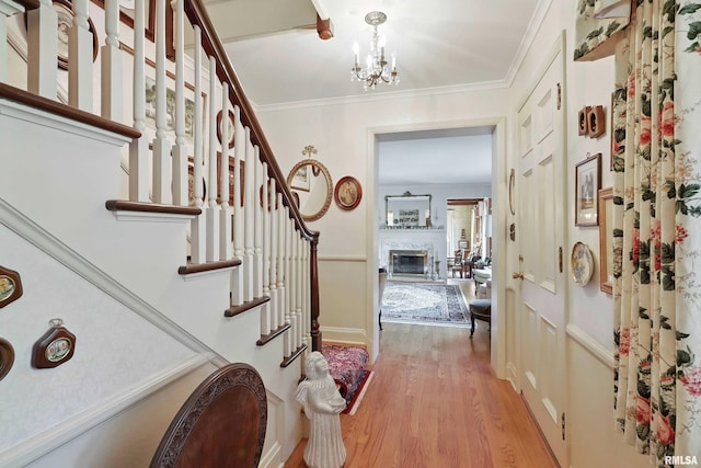1928 Fernwood Ave, Davenport, IA 52803 - entryway with light wood-style flooring, a glass covered fireplace, a chandelier, stairs, and crown molding
