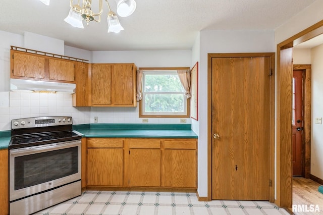 335 Sand Aly, Toronto, IA 52777 - kitchen featuring stainless steel electric range oven, under cabinet range hood, light flooring, a chandelier, and decorative backsplash