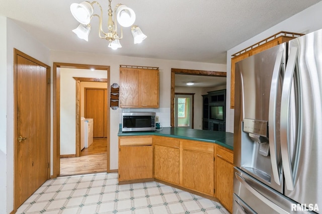 335 Sand Aly, Toronto, IA 52777 - kitchen featuring stainless steel appliances, light floors, a chandelier, washer / clothes dryer, and brown cabinets