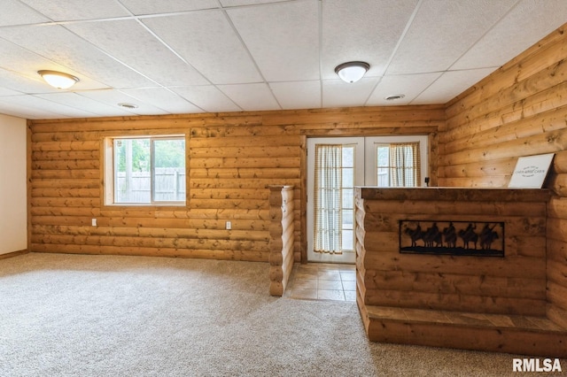 335 Sand Aly, Toronto, IA 52777 - unfurnished living room featuring plenty of natural light, carpet, log walls, and a glass covered fireplace