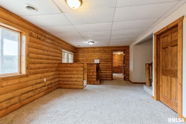 335 Sand Aly, Toronto, IA 52777 - unfurnished room with log walls, light carpet, and a paneled ceiling
