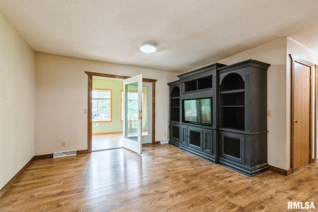 335 Sand Aly, Toronto, IA 52777 - spare room with light wood-style flooring, french doors, and a textured ceiling