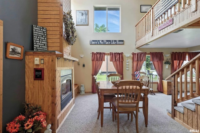 18599 317th St, Long Grove, IA 52756 - carpeted dining room featuring healthy amount of natural light, a towering ceiling, stairs, and a glass covered fireplace