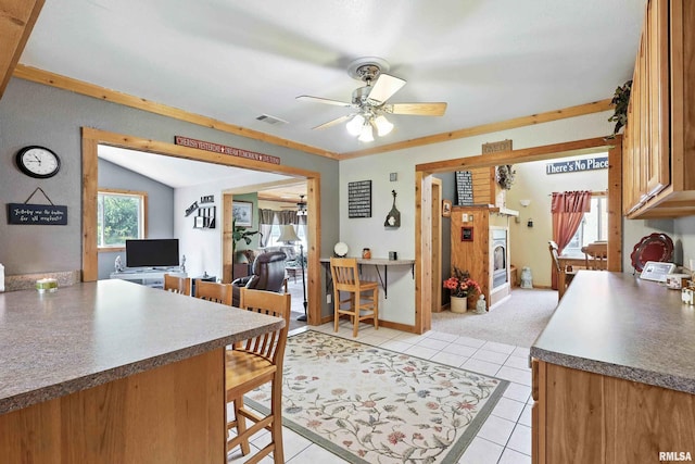 18599 317th St, Long Grove, IA 52756 - kitchen featuring a ceiling fan, light tile patterned floors, a breakfast bar, brown cabinetry, and dark countertops