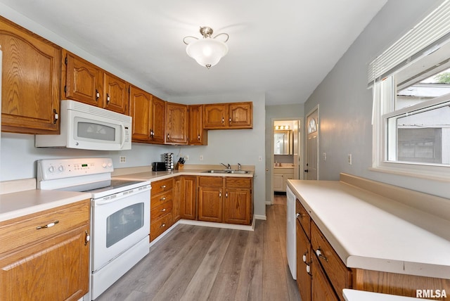 2506 Holly Dr, Bettendorf, IA 52722 - kitchen featuring white appliances, brown cabinetry, wood finished floors, and light countertops
