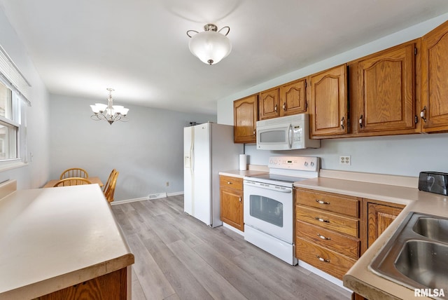 2506 Holly Dr, Bettendorf, IA 52722 - kitchen featuring white appliances, a chandelier, and brown cabinets