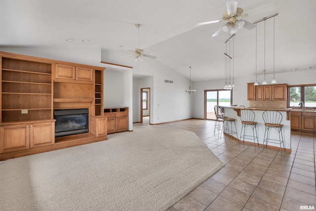 922 W Scott St, Eldridge, IA 52748 - unfurnished living room with ceiling fan, lofted ceiling, healthy amount of natural light, light tile patterned floors, and a glass covered fireplace