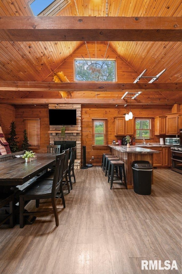 7319 106th Ave, Coal Valley, IL 61240 - dining room with wooden walls, wood finished floors, high vaulted ceiling, a wood ceiling with exposed beams, and a stone fireplace