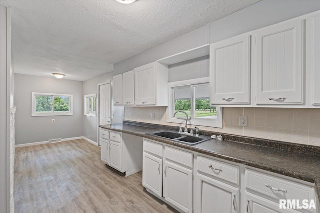 3916 W Locust St, Davenport, IA 52804 - kitchen with tasteful backsplash, dark countertops, white cabinetry, and a textured ceiling