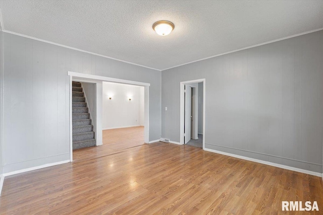 3916 W Locust St, Davenport, IA 52804 - empty room featuring light wood-type flooring, stairway, crown molding, and a textured ceiling