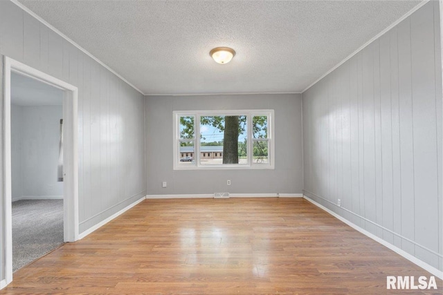 3916 W Locust St, Davenport, IA 52804 - unfurnished room with ornamental molding, light wood-style flooring, a textured ceiling, and wood walls