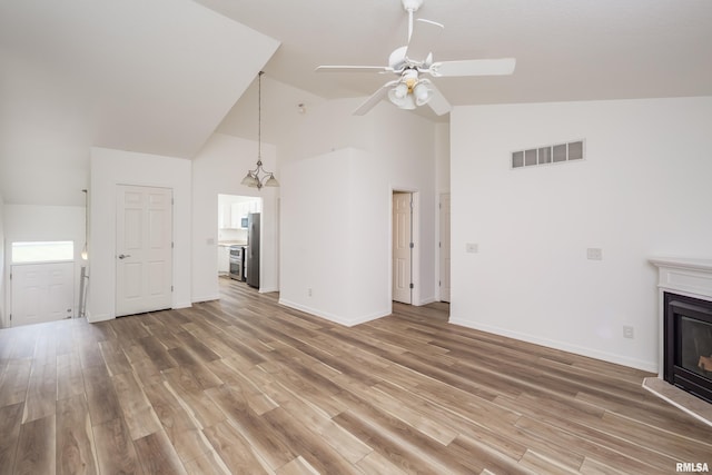 1263 33rd Avenue Cir, Silvis, IL 61282 - unfurnished living room featuring high vaulted ceiling, a ceiling fan, a glass covered fireplace, and light wood finished floors