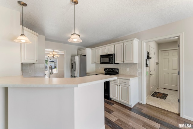 5320 Appleton Dr, Davenport, IA 52804 - kitchen featuring black appliances, tasteful backsplash, wood finished floors, a chandelier, and a textured ceiling