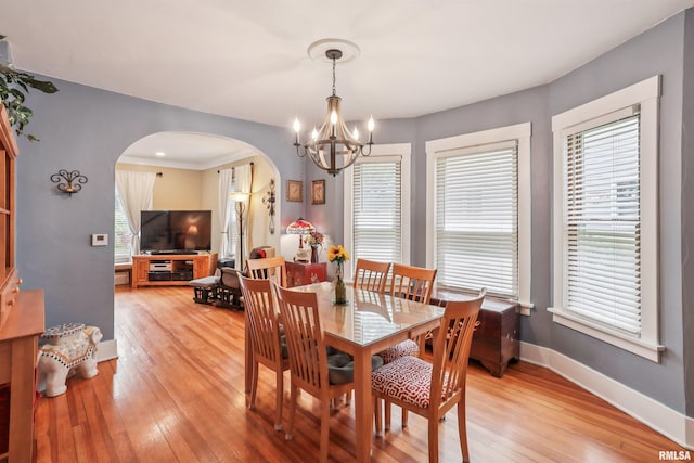 2510 Pershing Ave, Davenport, IA 52803 - dining room featuring arched walkways, a chandelier, light wood-style floors, and healthy amount of natural light