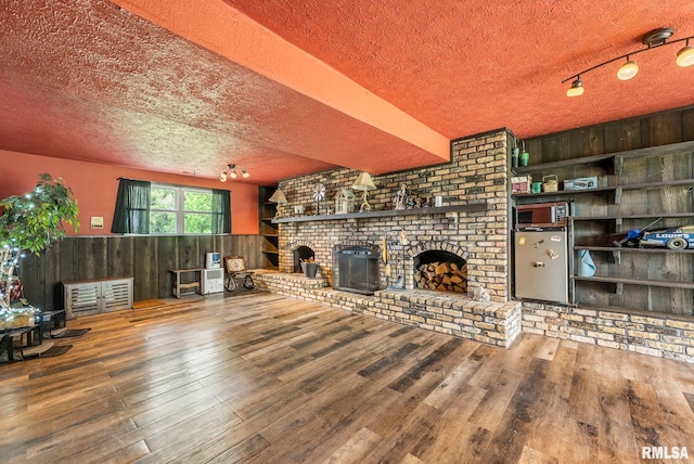 25622 1st Ave N, Hillsdale, IL 61257 - unfurnished living room featuring a textured ceiling, wood-type flooring, a fireplace, wood walls, and a wainscoted wall