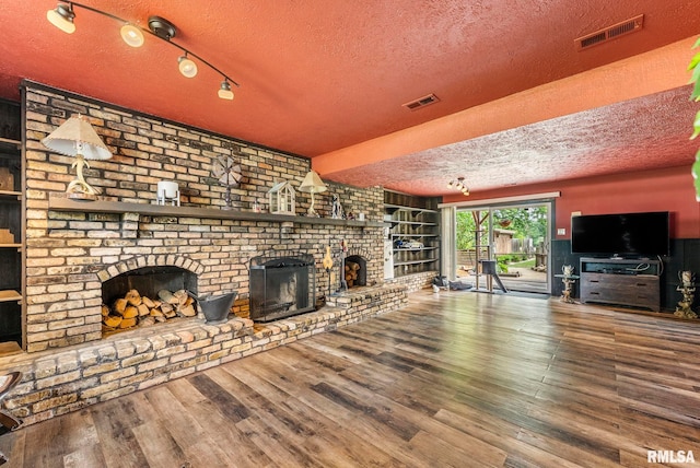 25622 1st Ave N, Hillsdale, IL 61257 - unfurnished living room featuring a textured ceiling, a fireplace, built in features, and wood finished floors