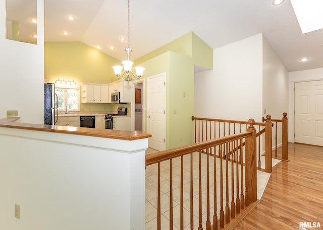 3439 Maple Glen Dr, Bettendorf, IA 52722 - kitchen with appliances with stainless steel finishes, lofted ceiling, a chandelier, a peninsula, and white cabinetry
