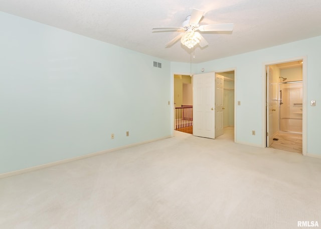3439 Maple Glen Dr, Bettendorf, IA 52722 - unfurnished bedroom featuring light carpet, a spacious closet, ensuite bathroom, and a ceiling fan