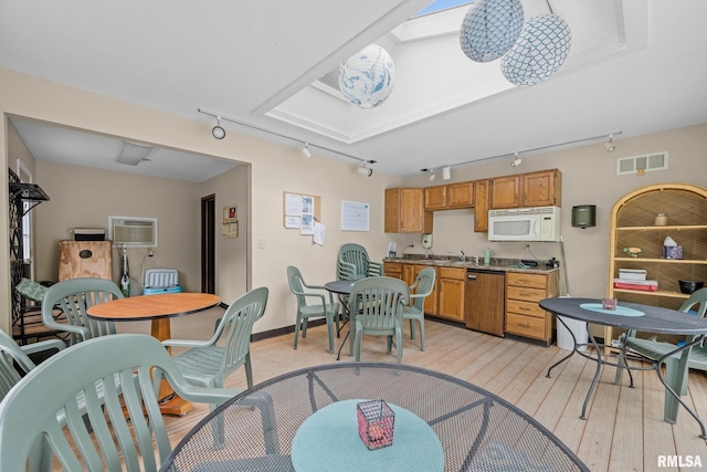 2809 12th Ave Unit 504, Rock Island, IL 61201 - kitchen with track lighting, dishwasher, white microwave, light wood-style floors, and a wall unit AC