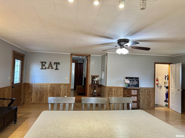653 Ferry Rd, Miles, IA 52064 - dining area with a wainscoted wall, wood walls, wood finished floors, crown molding, and ceiling fan
