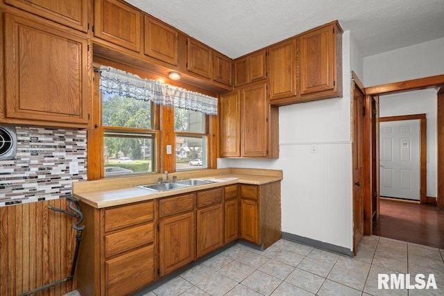 204 15th Ave, East Moline, IL 61244 - kitchen with decorative backsplash, brown cabinets, light countertops, light tile patterned floors, and a textured ceiling