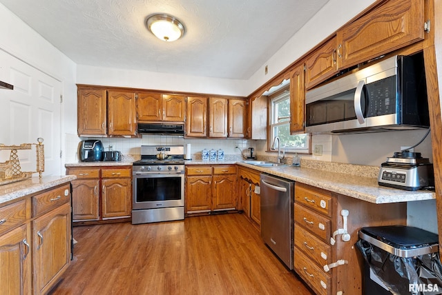 531 32nd Ave, East Moline, IL 61244 - kitchen featuring appliances with stainless steel finishes, exhaust hood, brown cabinets, dark wood-style flooring, and tasteful backsplash
