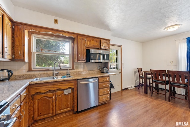 531 32nd Ave, East Moline, IL 61244 - kitchen with appliances with stainless steel finishes, brown cabinets, wood finished floors, plenty of natural light, and a textured ceiling