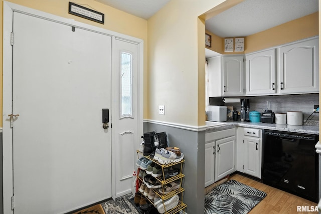3295 Johnathan Ave, Bettendorf, IA 52722 - kitchen featuring black dishwasher, light countertops, light wood-style flooring, decorative backsplash, and white cabinetry