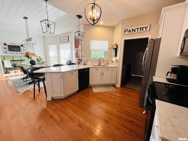 66 Windy Hill Dr, Murphysboro, IL 62966 - kitchen with black appliances, a peninsula, decorative light fixtures, light wood-type flooring, and white cabinets