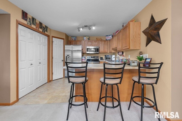 3209 S 16th Ave Unit 203, Eldridge, IA 52748 - kitchen featuring stainless steel appliances, a peninsula, light countertops, a kitchen breakfast bar, and light colored carpet