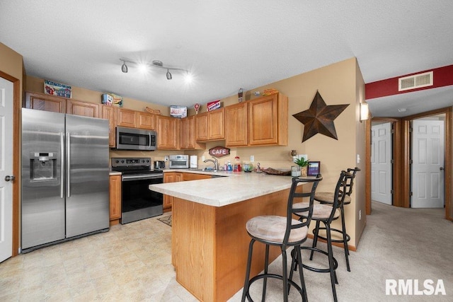 3209 S 16th Ave Unit 203, Eldridge, IA 52748 - kitchen with appliances with stainless steel finishes, a peninsula, light countertops, a breakfast bar, and rail lighting