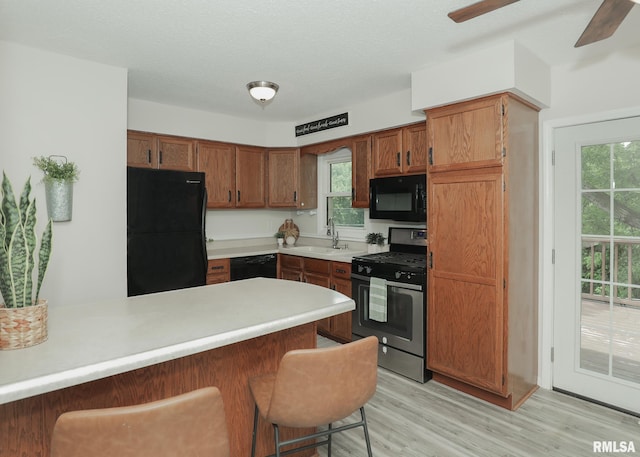 5022 Northbrook Ct, Davenport, IA 52806 - kitchen featuring black appliances, a peninsula, a breakfast bar, and light wood finished floors
