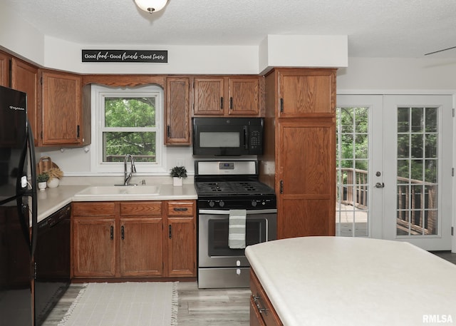 5022 Northbrook Ct, Davenport, IA 52806 - kitchen with black appliances, light wood-type flooring, light countertops, a textured ceiling, and brown cabinetry