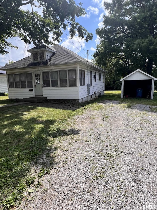 202 N Wilson St, Anna, IL 62906 - view of front facade featuring a sunroom, a front lawn, a shingled roof, driveway, and a detached carport