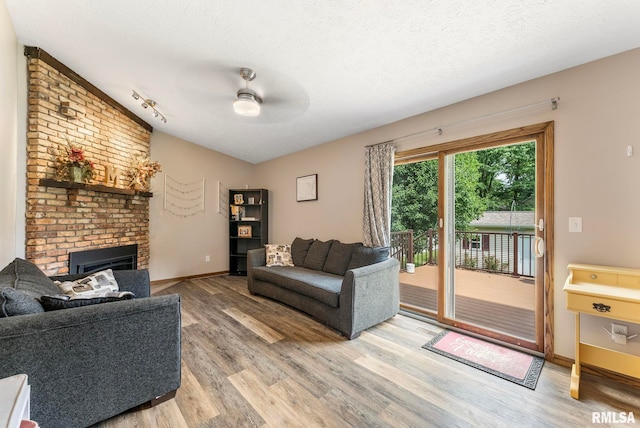 303 S Park View Dr, Park View, IA 52748 - living area with light wood-style floors, ceiling fan, a textured ceiling, a brick fireplace, and lofted ceiling
