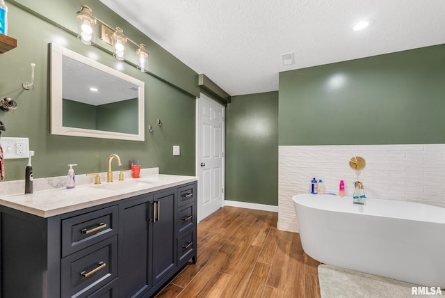 303 S Park View Dr, Park View, IA 52748 - bathroom with a freestanding bath, vanity, wood finished floors, a textured ceiling, and tile walls