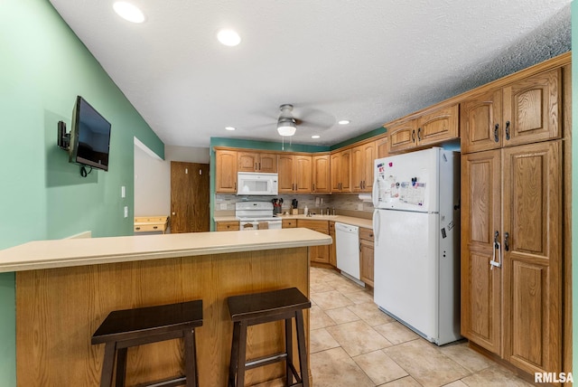 303 S Park View Dr, Park View, IA 52748 - kitchen with white appliances, ceiling fan, light countertops, a breakfast bar area, and light tile patterned floors