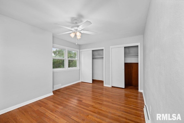 1815 Lincoln Rd, Bettendorf, IA 52722 - unfurnished bedroom with two closets, wood finished floors, and ceiling fan