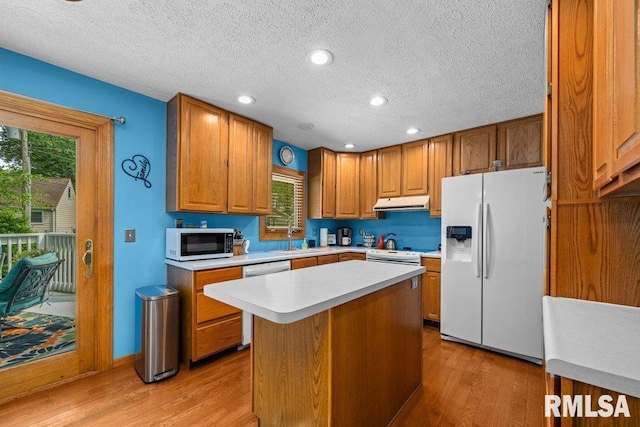 2401 W Dale Ct, Bettendorf, IA 52722 - kitchen with white appliances, light countertops, a textured ceiling, light wood-style floors, and under cabinet range hood
