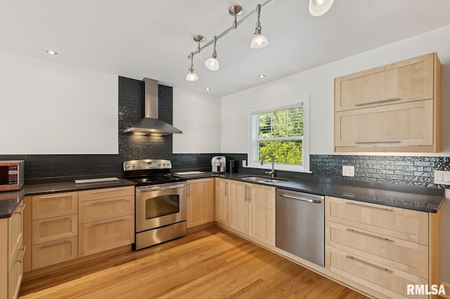 1928 Elm St, Davenport, IA 52803 - kitchen featuring light brown cabinetry, wall chimney exhaust hood, appliances with stainless steel finishes, dark countertops, and recessed lighting