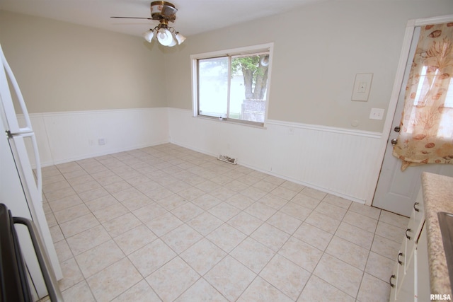 3618 18th St, Bettendorf, IA 52722 - unfurnished dining area featuring wainscoting, a ceiling fan, and light tile patterned floors