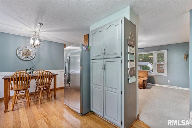 1215 Calvin St, Davenport, IA 52804 - kitchen featuring stainless steel fridge, a textured ceiling, a chandelier, light wood-type flooring, and hanging light fixtures