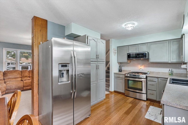 1215 Calvin St, Davenport, IA 52804 - kitchen with stainless steel appliances, gray cabinets, light wood-style floors, backsplash, and light countertops